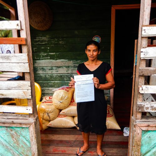A female resident of the Brazilian Rosewood project holding a certificate of land tenure.