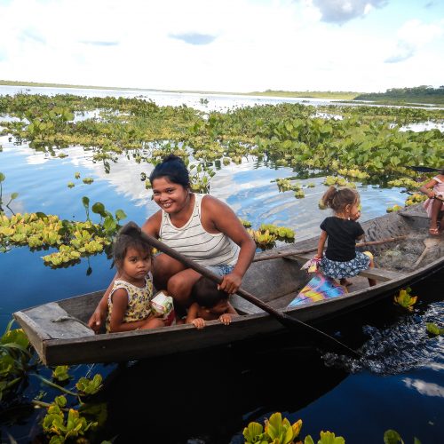 A resident family of the Brazilian Rosewood project paddling in a canoe in shallow waters and wetlands.